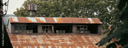 Old Rusty Metal Roof With Windows And Trees In Background
