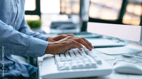A person typing on a computer keyboard in an office setting.