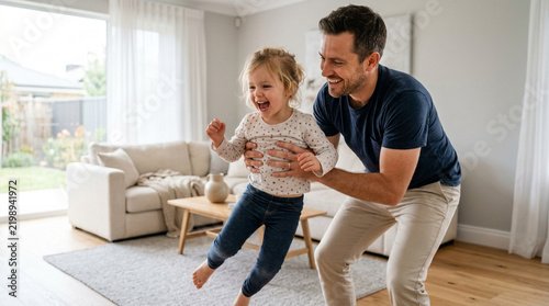 Father lifting happy daughter playing in living room, family fun, indoor childhood