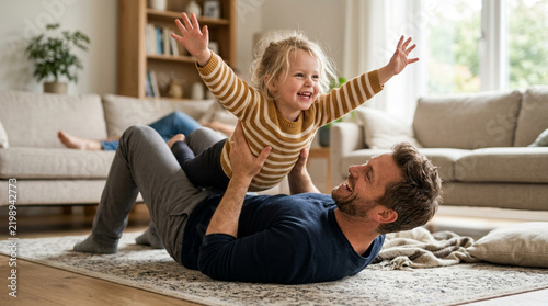 Father playfully lifting happy child in living room, family lifestyle
