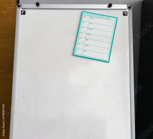 Fotografie Blank whiteboard with turquoise bordered weekly planner sheet attached by magnet