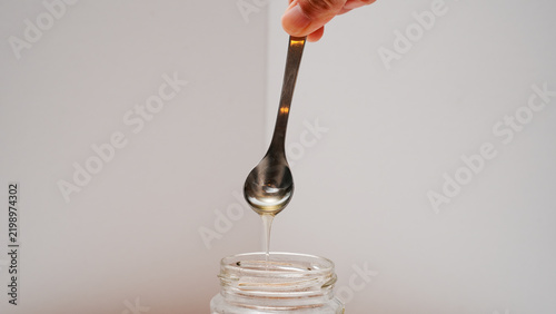 Принти на полотні Spoon drizzling honey into a glass jar