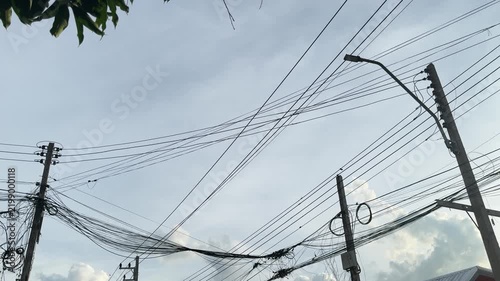 Chaotic messy electric wires and cables on poles against sky background