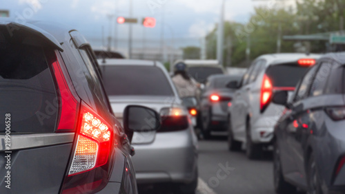 Rear side of grey car with turn on brake light on asphalt road. Vehicles wait in heavy traffic congestion on an urban street with brake lights glowing bright red. Cars were lined up densely.