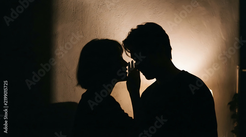 Silhouette of a man whispering a secret to a woman in a dimly lit room with body language whispering silhouette communication intimate mysterious darkness dialogue connection relationship