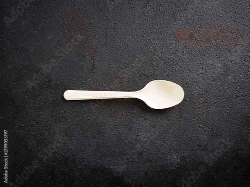 Tapety artystyczne Disposable compostable spoon on dark background