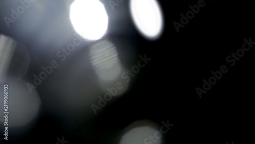 Fotografie Abstract white bokeh light orbs on a deep black background