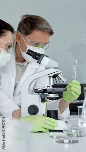 Fotografie Scientist working with microscope researching medical analysis discovering biolo