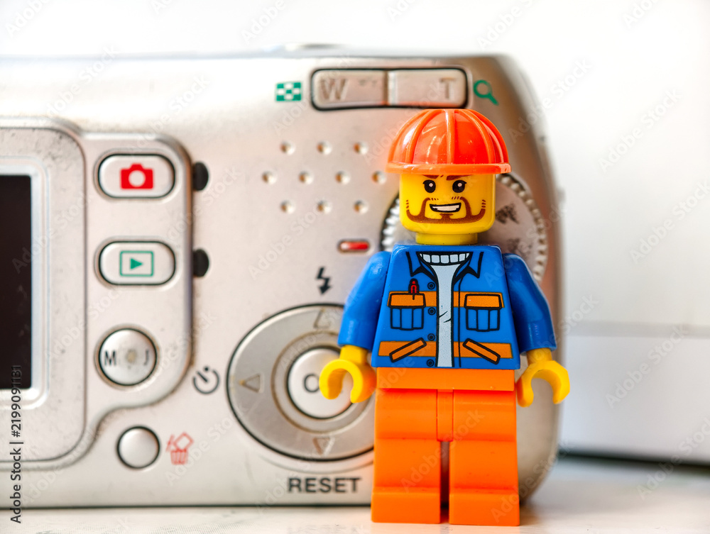 Fototapeta premium Russia, St. Petersburg, August 8, 2020 A lego man standing next to a camera, great for creative illustrations, cartoons, or even a toy photography setup