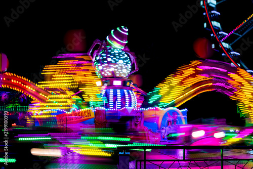 Brightly Lit Carnival Ride Spinning in Motion with Neon Light Trails at Night