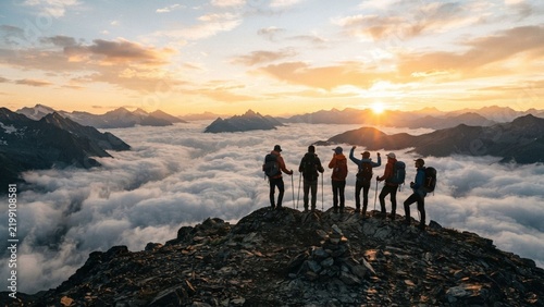 Silhouette of Hikers Standing on Mountain Peak Above Clouds at Sunset