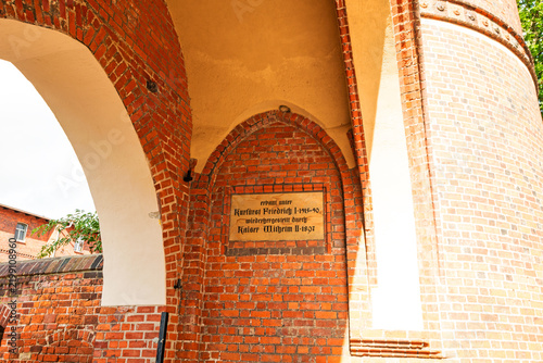 Historic inscription set into the brickwork of a medieval gate, referring to its construction and restoration, photographed in landscape format.