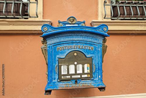Historic-style blue post box with ornate metal decoration on a building facade in Tangermünde, photographed in landscape format.