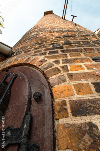 Low-angle view of the historic Schrotturm with medieval brickwork and wooden door with iron fittings, photographed in portrait format.