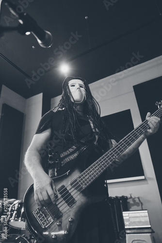 Foto Masked male bassist performing during studio rehearsal under spotlight