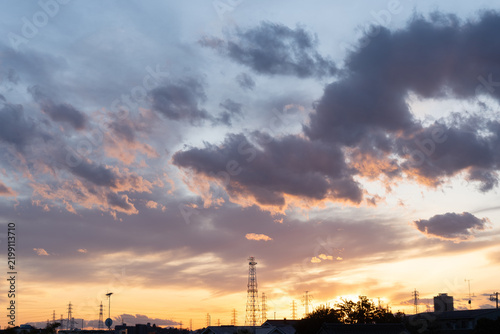 夕焼けの空に広がる水色、ピンク、グレー、オレンジの雲と都市の夕景