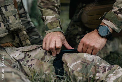 Military soldier applies a tourniquet to the leg of a wounded comrade. Combat tactical equipment. Combat use Turnstile.