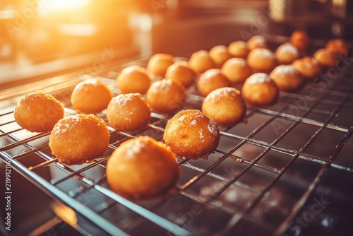 Freshly fried paczki cooling on a rack in a bakery