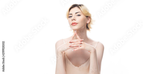A young blonde girl with clear skin in a satin top. Beauty portrait of a woman on a white background in the studio.