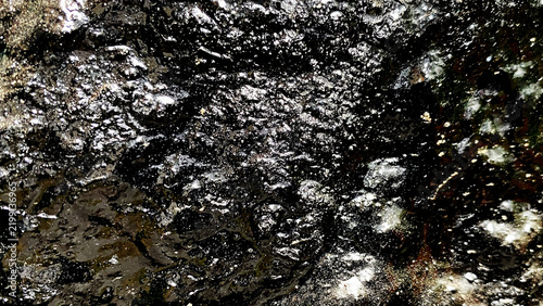 Wet dark glossy muddy rock ground surface texture