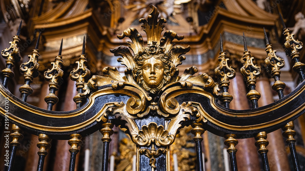 Fototapeta premium Ornate golden baroque railing with classical face sculpture