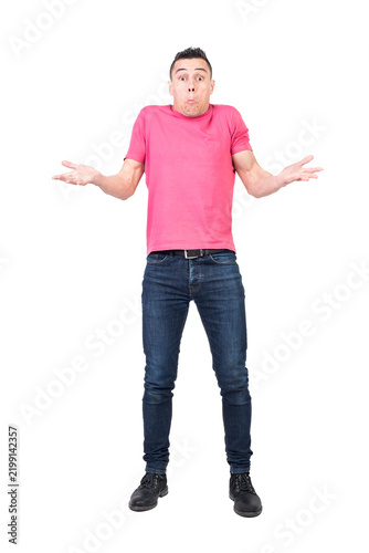 Obraz na płótnie Full length of young uncertain man in t shirt and jeans shrugging shoulders and