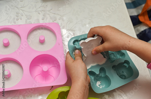 Canvastavla Child removes plaster shapes from silicone molds on crafting table, holding tray carefully