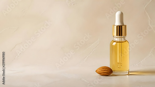Glass Dropper Bottle with Golden Serum and Almond Nut on Beige Background