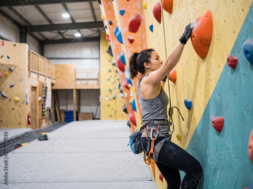 Young woman climbing a rock wall in a climbing gym  