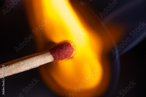 Obraz na plátně Single wooden match igniting with bright orange flame and glowing red match head