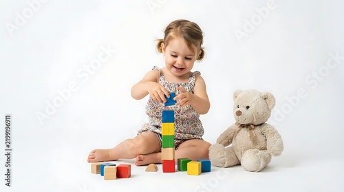 A toddler girl building a tower with colorful blocks