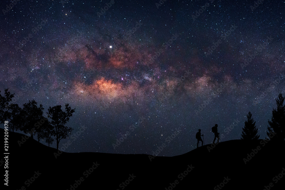 Fototapeta premium Landscape with Milky Way. Night sky with stars and silhouette of a standing happy man on the mountain, Success or winner, leader concept. High iso with Noise.