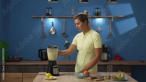 Young fit woman making detox cocktail using blender in kitchen. Smoothie for healthy diet. Vitamins. Cooking breakfast in the kitchen