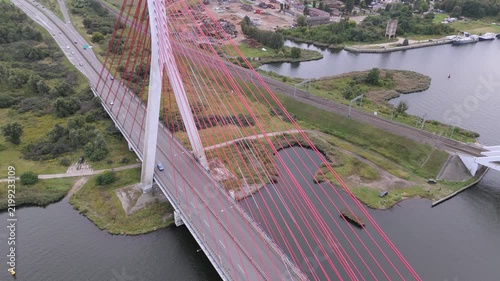 High-angle drone view of a contemporary cable-stayed bridge spanning a water body with traffic.