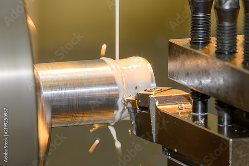 Close up of a metal shaft finish cutting process on a lathe machine using a liquid coolant method