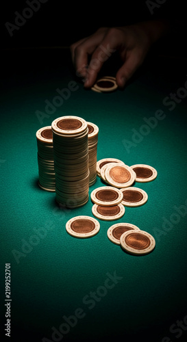 Stacks of poker chips on a green felt surface, with a hand reaching to add another chip, symbolizing chance, risk, and gambling