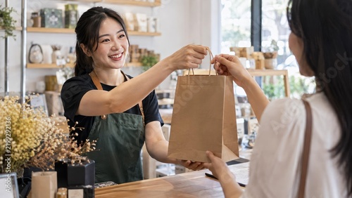 Small Business Owner Providing Excellent Customer Service: Handing Over a Shopping Bag to Satisfied Customer Across the Counter. Retail Transaction Concept in Action