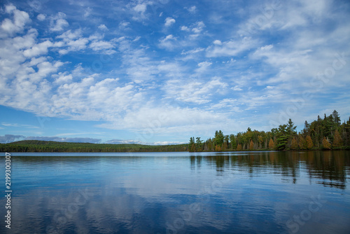 Beautiful calm blue northern Minnesota lake with pines on the shore and clouds above