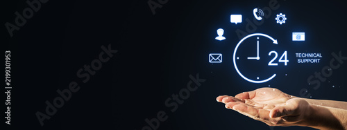 24-hour technical support concept with glowing hologram icons above an open businessperson hand on dark blue technology background for marketing.