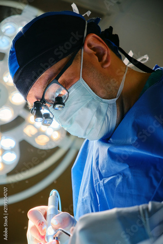 Focused surgeon wearing magnifying loupes during surgery in an operating room