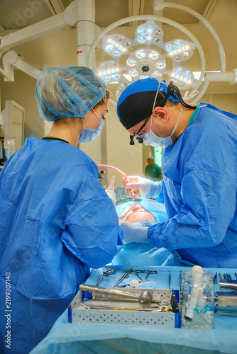 Surgeon and assistant performing surgery under operating room lights