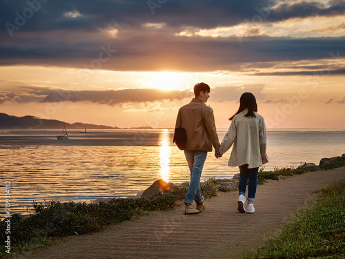 カップルが夕日を眺めて海辺を散歩