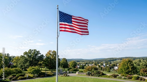 A flagpole with an American flag waving in the wind against a clear blue sky.