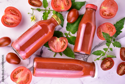 Bottled tomato juice on a white background and fresh tomatoes. Flat lay.
