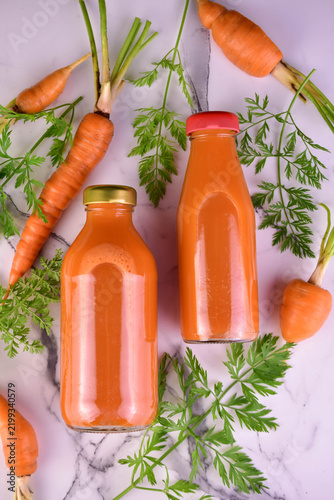 Carrot juice in small bottles on a white background. Flat lay.
