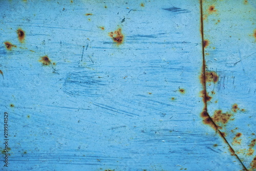 Light blue scratched painted metal texture with a rusty seam and brown corrosion spots. Weathered grunge industrial background surface. Close up macro detail for 3D modeling and abstract urban decor.