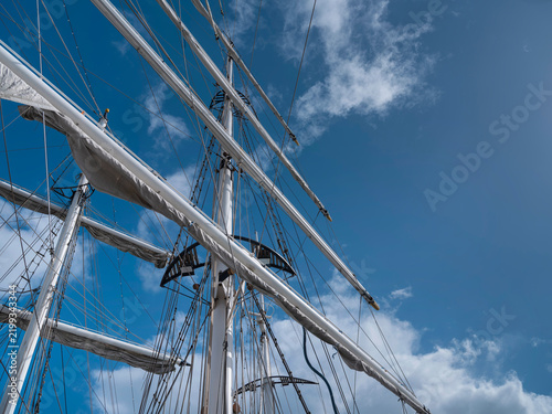 Fotografía Masts and yards of a square rigged tall ship with furled sails stand out against a bright blue summer sky