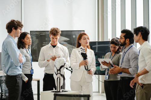 Diverse technology professionals collaborating around a humanoid robot while discussing artificial intelligence, robotics, research, and innovation in a modern workplace.