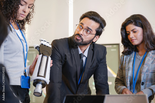 Technology professionals examining a robotic prototype and discussing its design and development in a modern research and engineering environment.