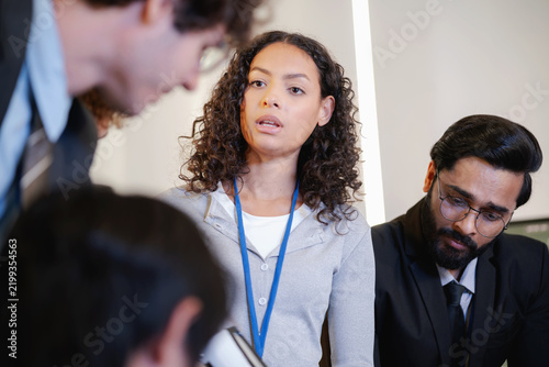 Female technology professional speaking to colleagues during a collaborative discussion in a modern research and development workplace.